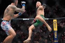 Conor McGregor, right, jumps into the air for a kick as he fights Max Holloway in a welterweigh ...