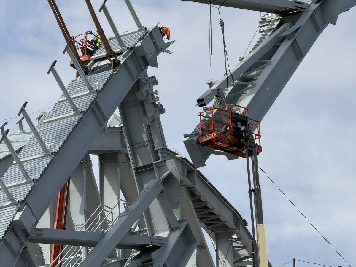 A portion of the second roof truss being lifted into place by construction workers at the Athle ...