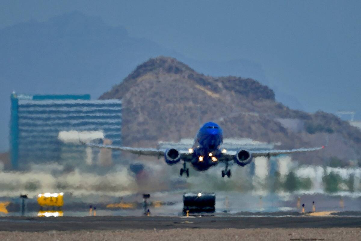 A jet takes flight as heat ripples radiate from the runway at Sky Harbor International Airport ...