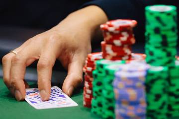 A poker player keeps his hand on a card during the World Series of Poker Main Event at Horsesho ...