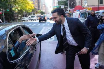 New York City mayoral candidate Zohran Mamdani greets some people in a car while surrounded by ...