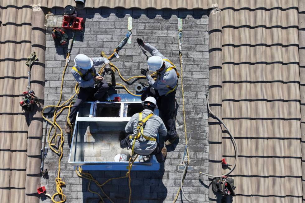 Workers from Grandview Construction prepare to install a new air conditioning unit on a home Tu ...