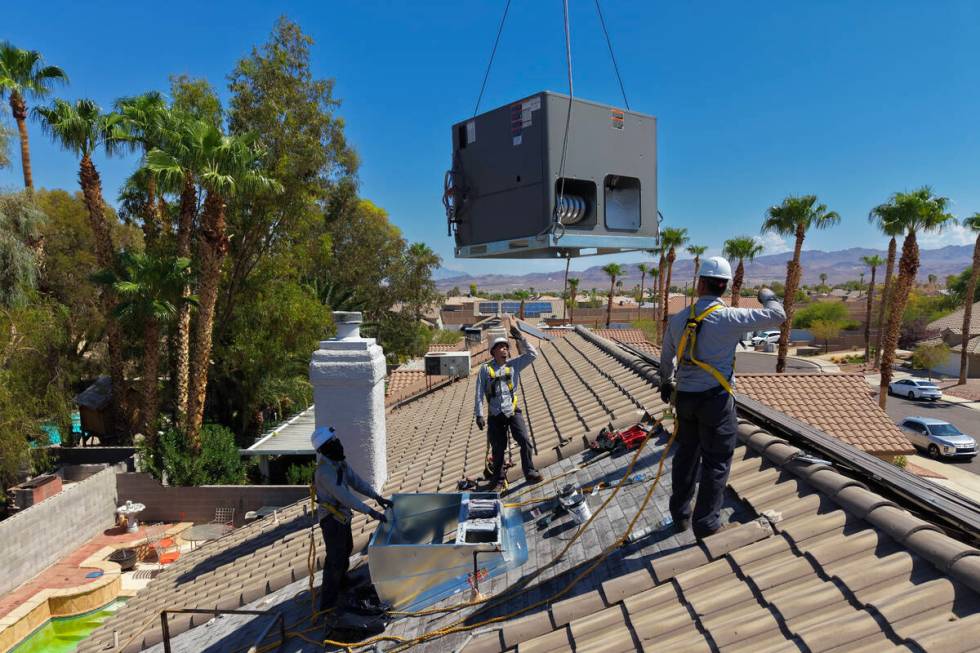 Workers from Grandview Construction guide a new air conditioning unit onto a home Tuesday, Augu ...