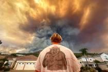 Aidan Thomas wears a Smokey Bear t-shirt as he watches smoke from the Airport Fire rise behind ...