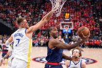 LA Clippers forward Kawhi Leonard, center, shoots as Golden State Warriors center Kristaps Porz ...