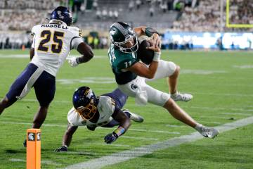 Michigan State quarterback Alessio Milivojevic, right, is forced out of bounds on a keeper by T ...