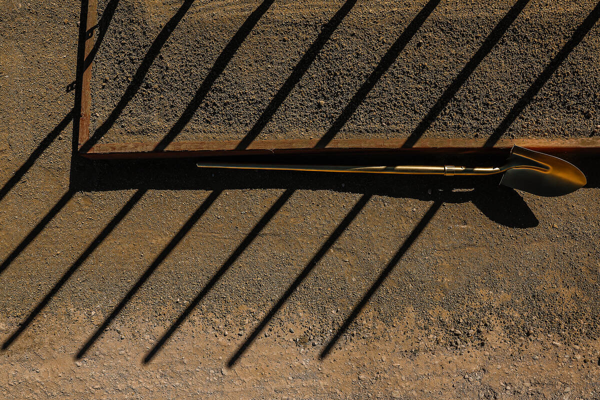 Overhead view of a golden ceremonial shovel resting on dirt at the Jewel apartment groundbreaking site in Las Vegas Chinatown