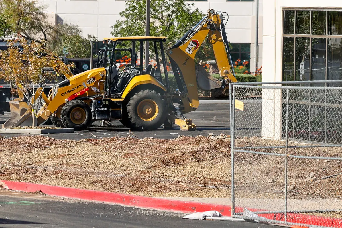 A backhoe works behind construction fencing at the office buildings on Paseo Verde Parkway in Henderson that are being converted into The Cliff