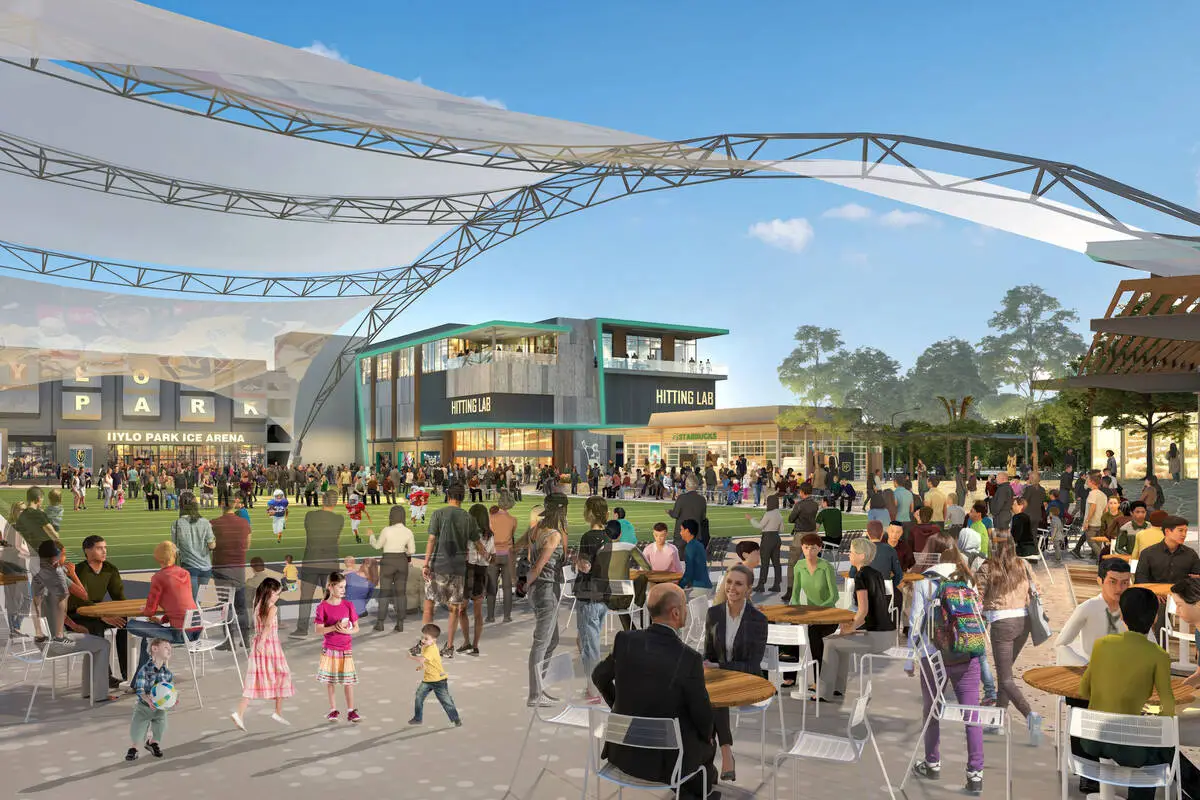 Rendering of the planned Hylo Park community lawn in North Las Vegas with families at tables under a shade canopy, a hitting lab building and the ice arena in the background