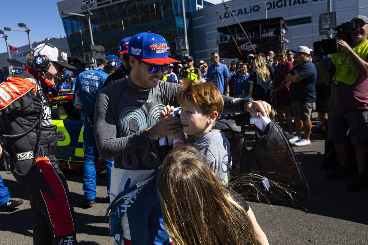 Driver Kyle Larson hands a pre-race vest to his son Owen before the start of the South Point 40 ...